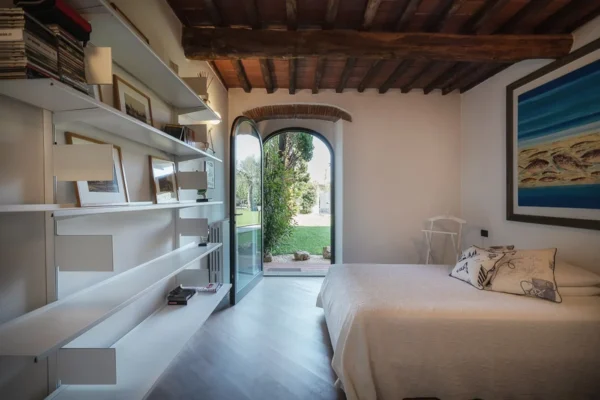 Bedroom with wooden beams and an arched French door onto the garden