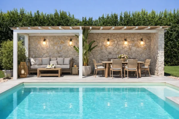 Stone pergola with outdoor lounge and dining table by the pool of the holiday apartments