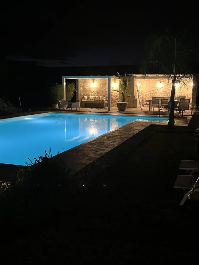 The pool at night beside the lit stone pergola